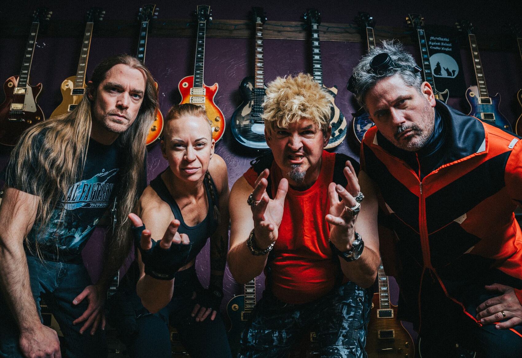 The A.D.A.M. Music Project band in front of a wall of guitars